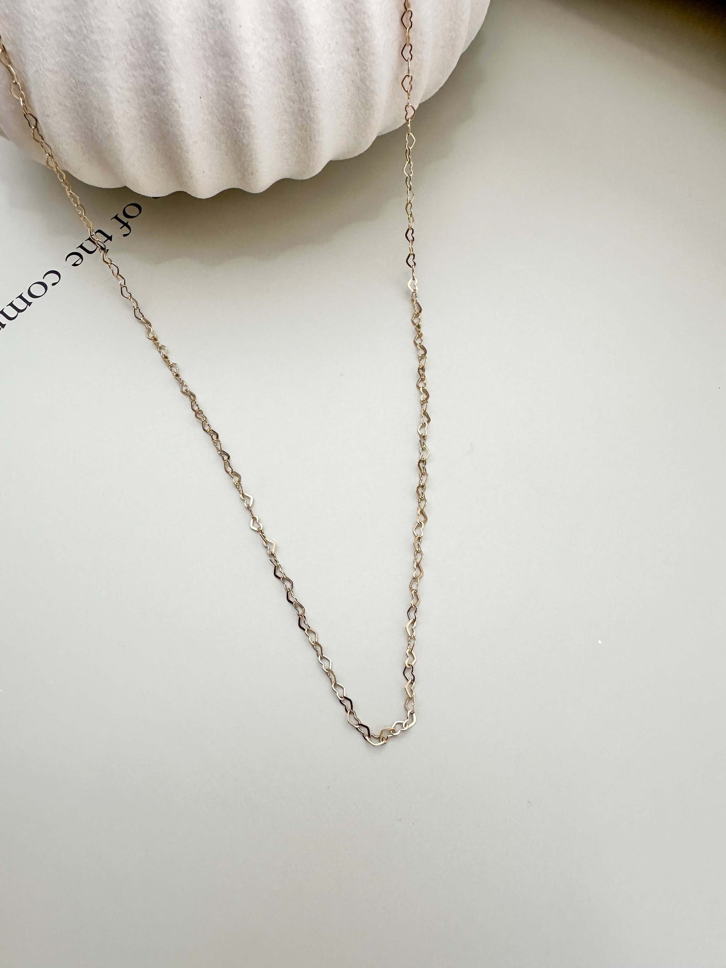 Gold filled dainty flat heart necklace chain on light background, hypoallergenic and waterproof for everyday wear.