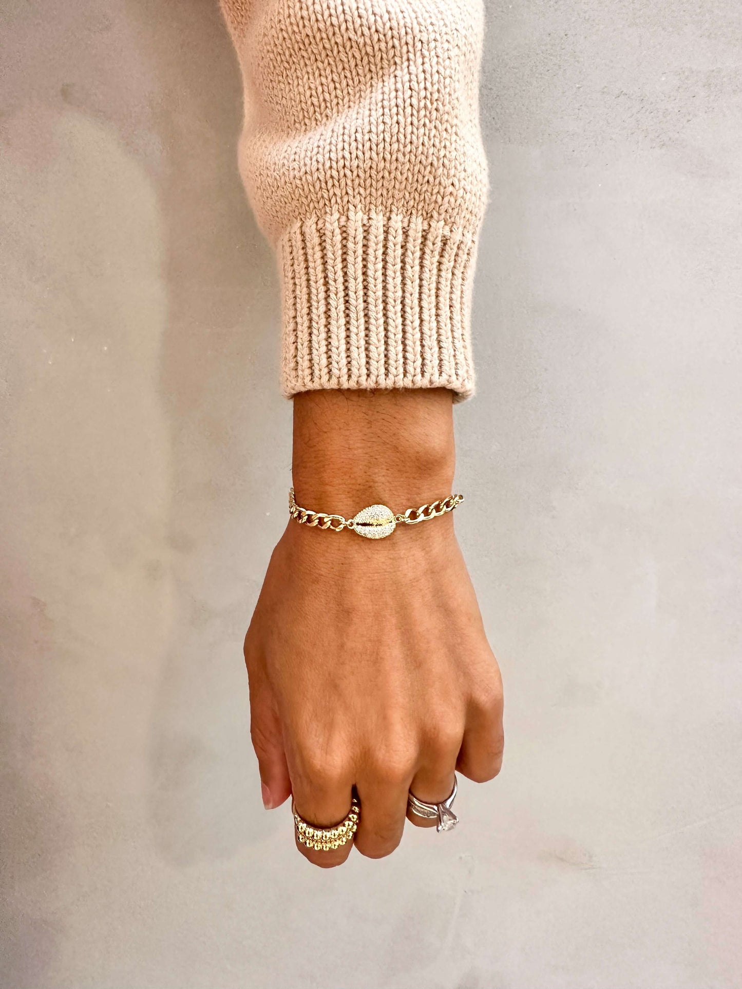 Elegant hand wearing a Velani Jewelry Cowrie Cuban Bracelet, showcasing its gold filled design and stylish appeal.
