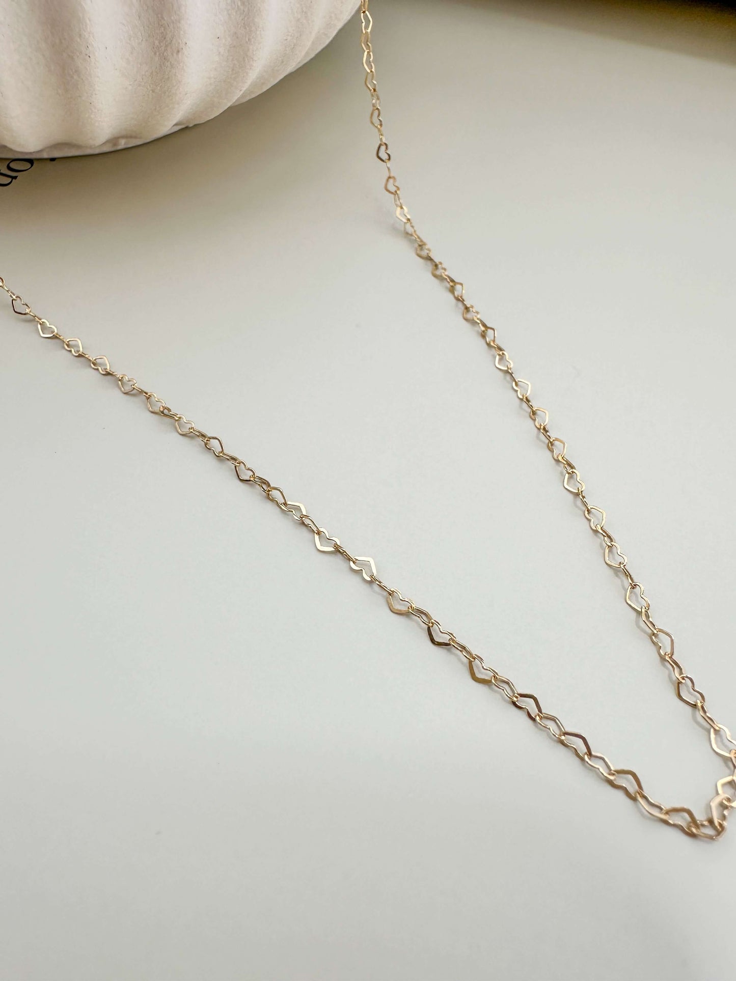 Gold filled dainty flat heart necklace on a neutral background, hypoallergenic and tarnish resistant for everyday wear.