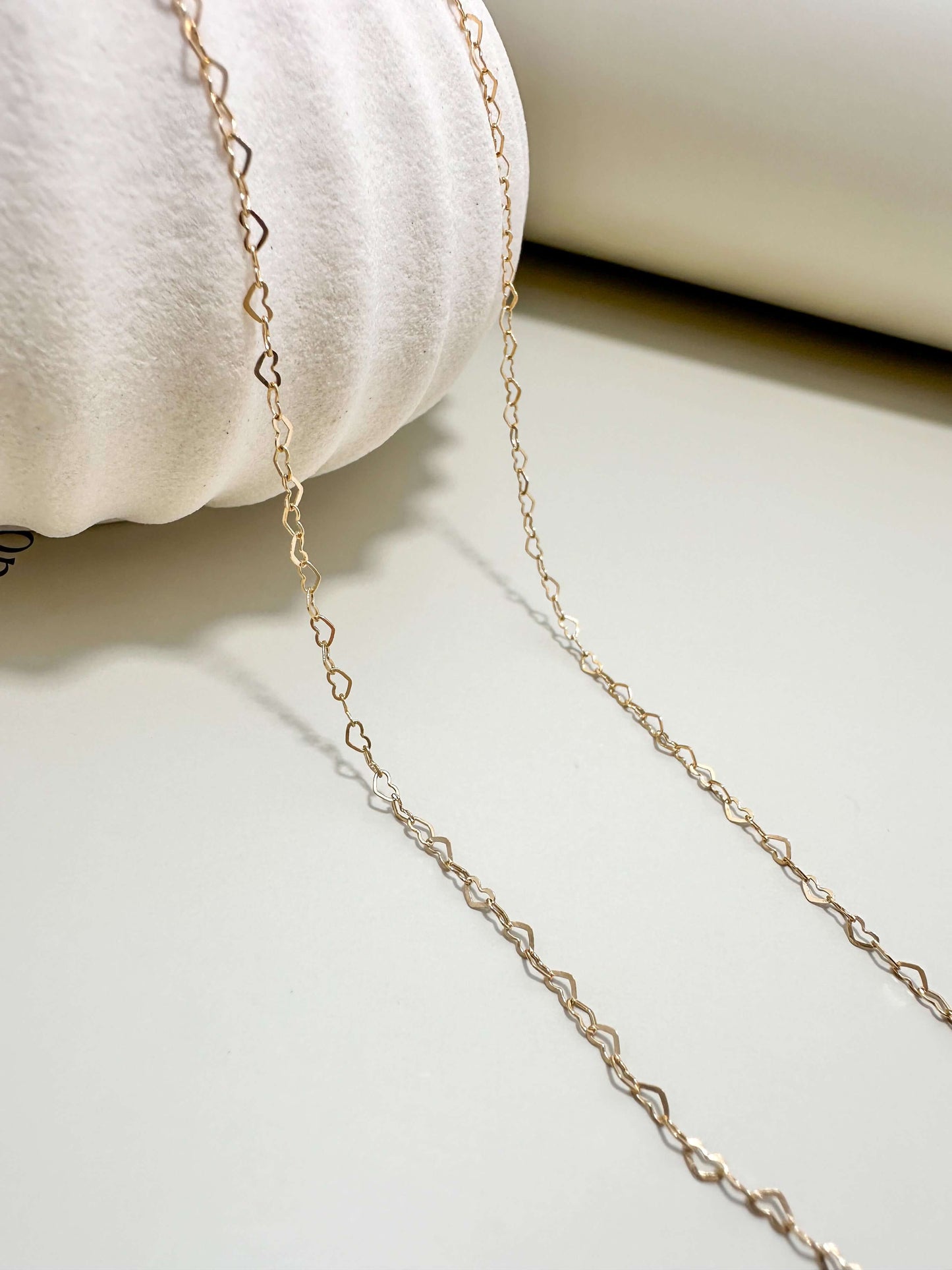 Gold filled dainty flat heart necklace on a neutral background, perfect for everyday wear, hypoallergenic and waterproof.