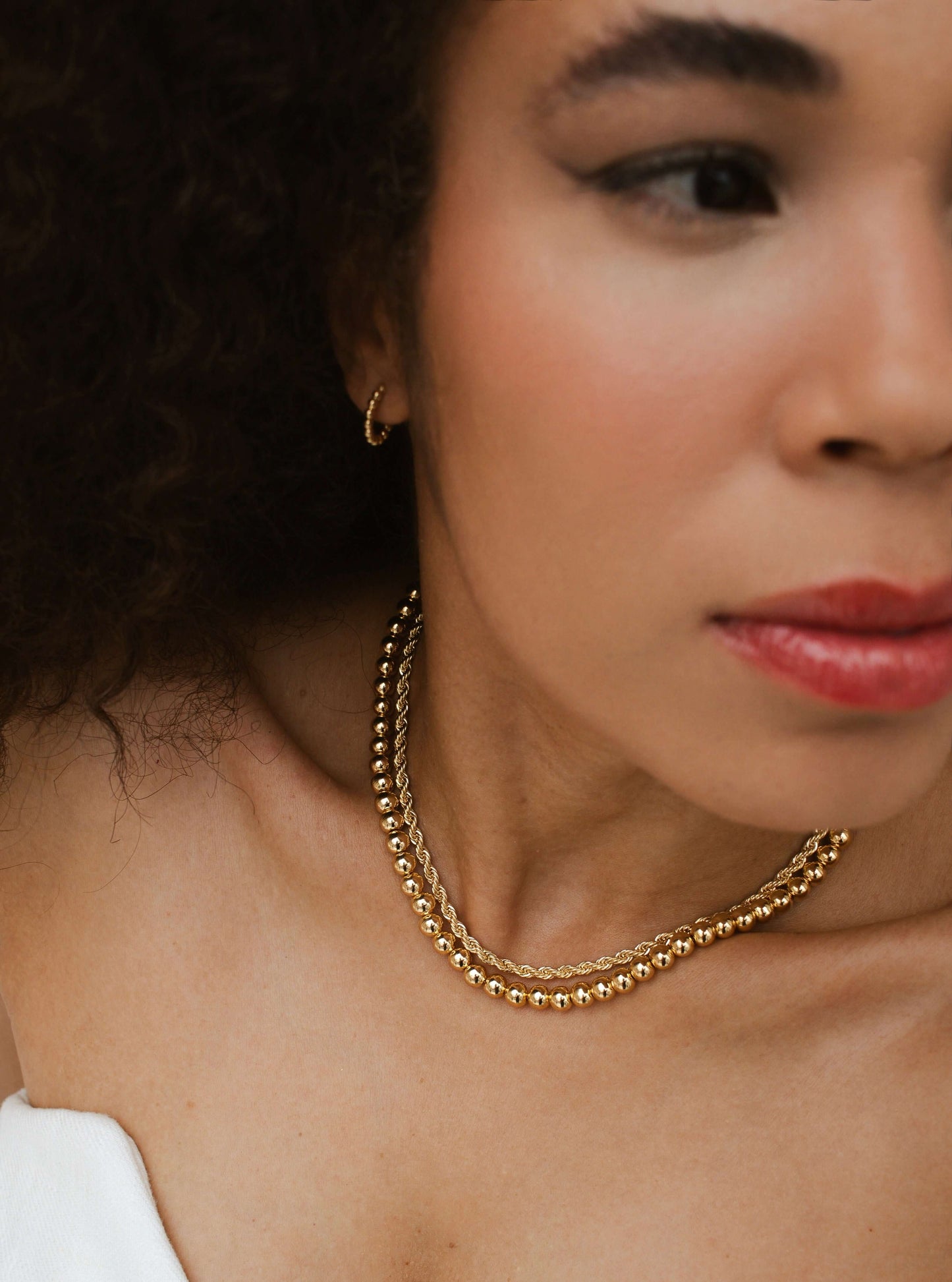Close-up of woman wearing a Velani Jewelry 18K gold big beads necklace, showcasing its shine and elegant design.