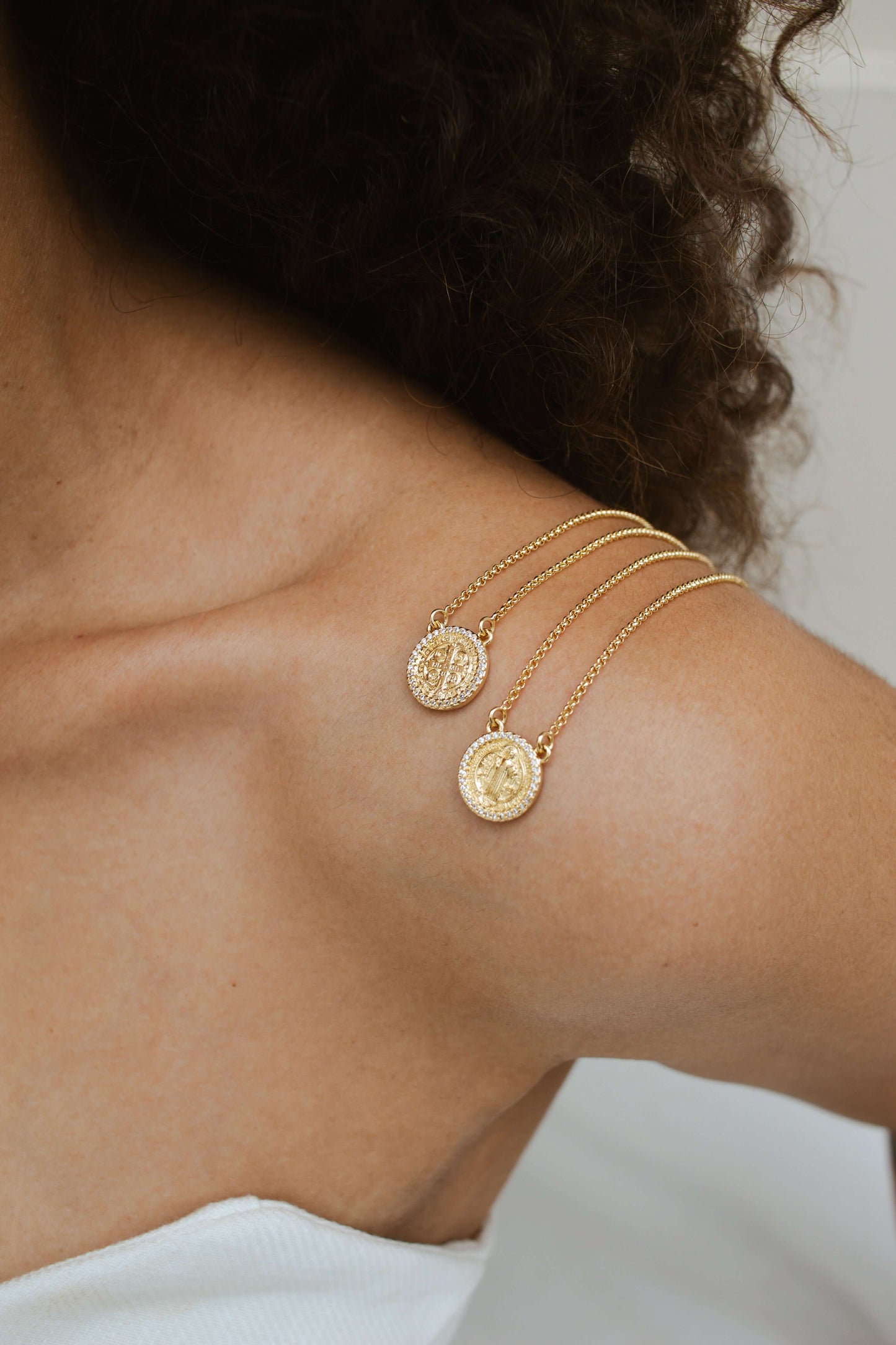Close-up of Velani Jewelry Saint Benedict Scapular Necklace on shoulder, featuring gold-filled, hypoallergenic design.