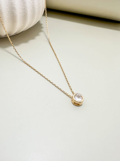 Velani Jewelry solitaire diamond necklace in 18K gold filled design with 6.5mm pendant on a smooth surface.