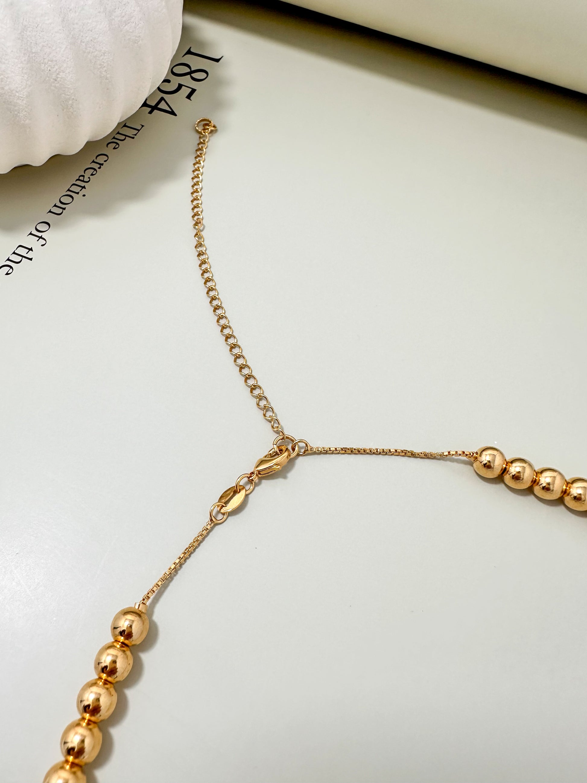 Velani Jewelry Big Beads Necklace clasp detail, showcasing 18K gold and rhodium plating on a light background.