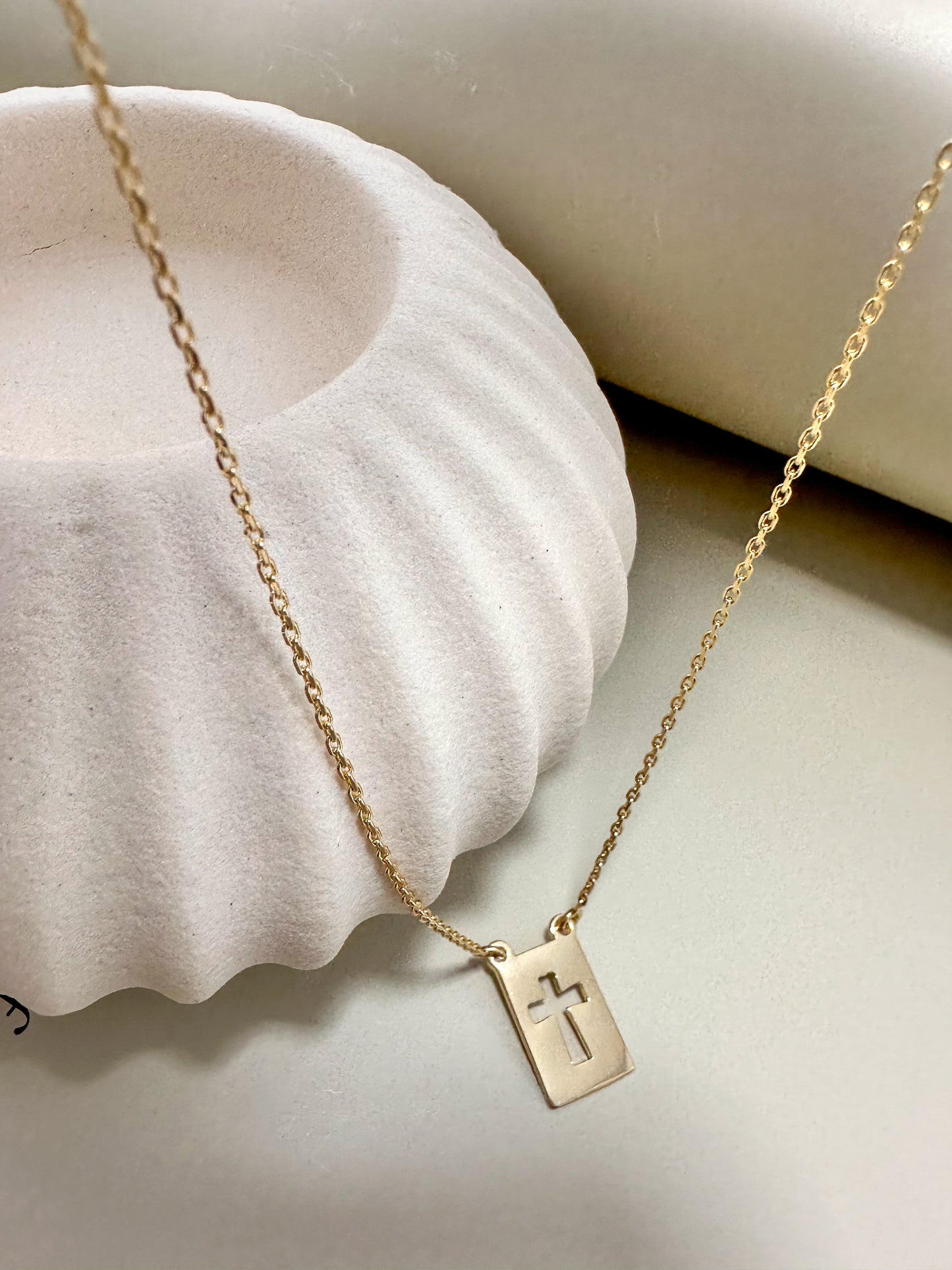 Velani Jewelry El Shaddai Cross Plaque Necklace on a soft background, showcasing its minimalist gold design and elegant charm.