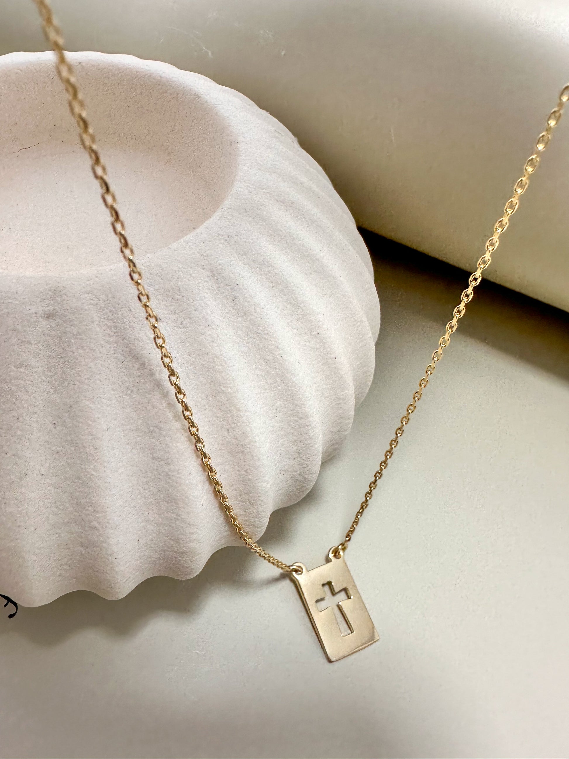 Velani Jewelry El Shaddai Cross Plaque Necklace on a soft background, showcasing its minimalist gold design and elegant charm.