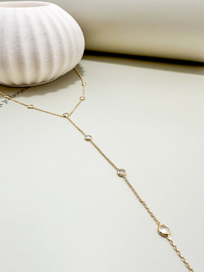 Velani Jewelry Lariat Necklace with Cubic Zirconia showcasing gold chain and sparkling stones, styled with a modern vase.