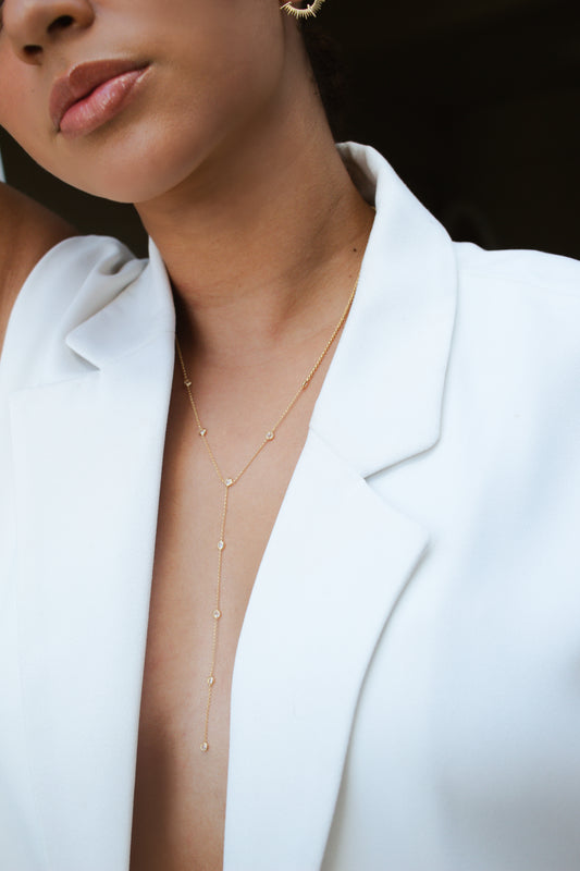 Velani Jewelry Lariat Necklace with Cubic Zirconia worn by a model, showcasing a chic gold design against a white blazer.