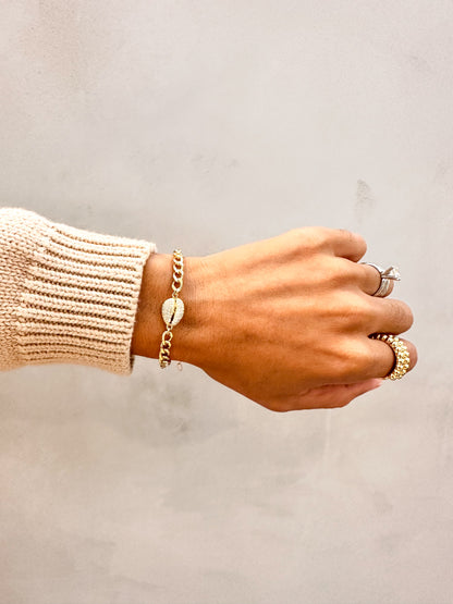 Hand wearing Velani Jewelry Cowrie Cuban Bracelet with additional rings, showcasing an elegant island style.