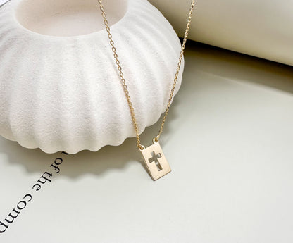 Velani Jewelry El Shaddai Cross Plaque Necklace on a textured surface, showcasing elegant minimalist design.