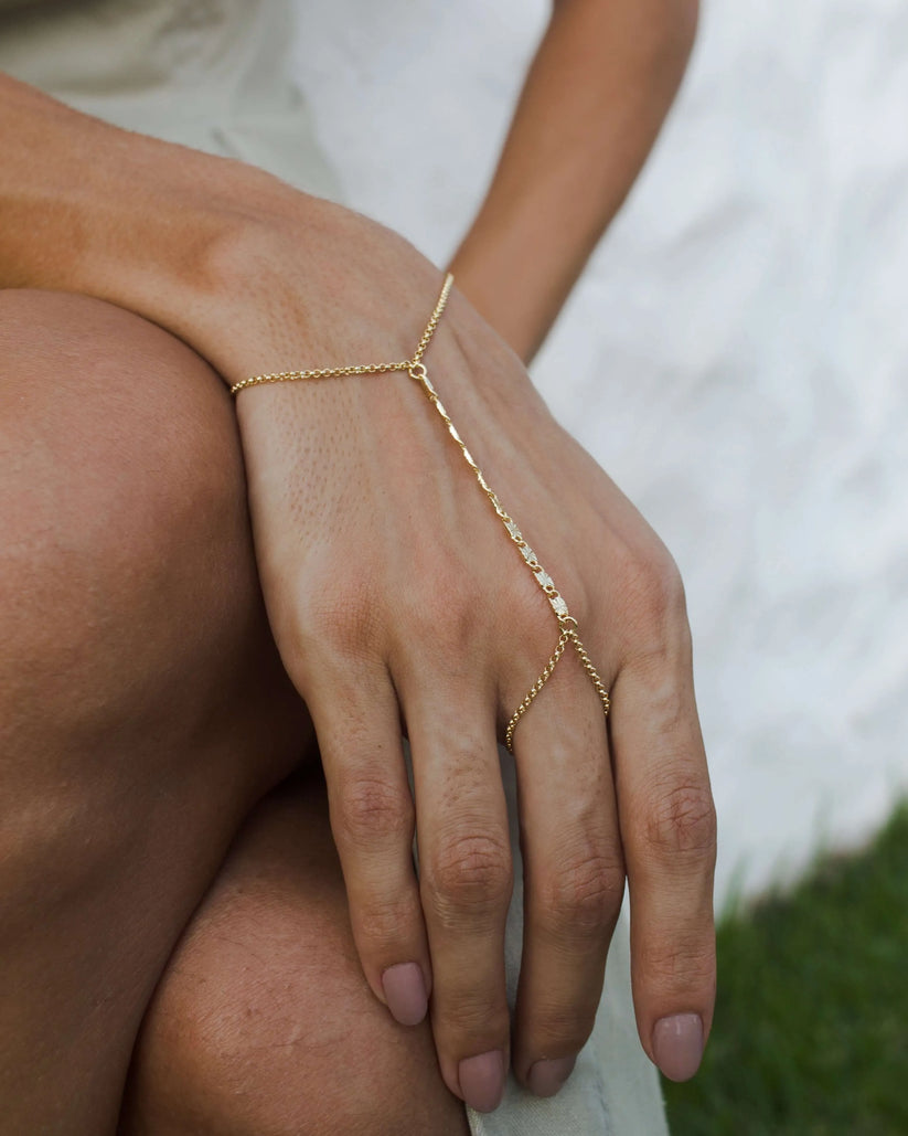 Gold-filled hand chain bracelet styled with layered jewelry