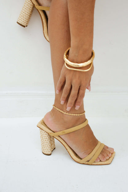 Woman wearing beige strappy heels and a Velani Jewelry brushed bangle bracelet for everyday fashion.