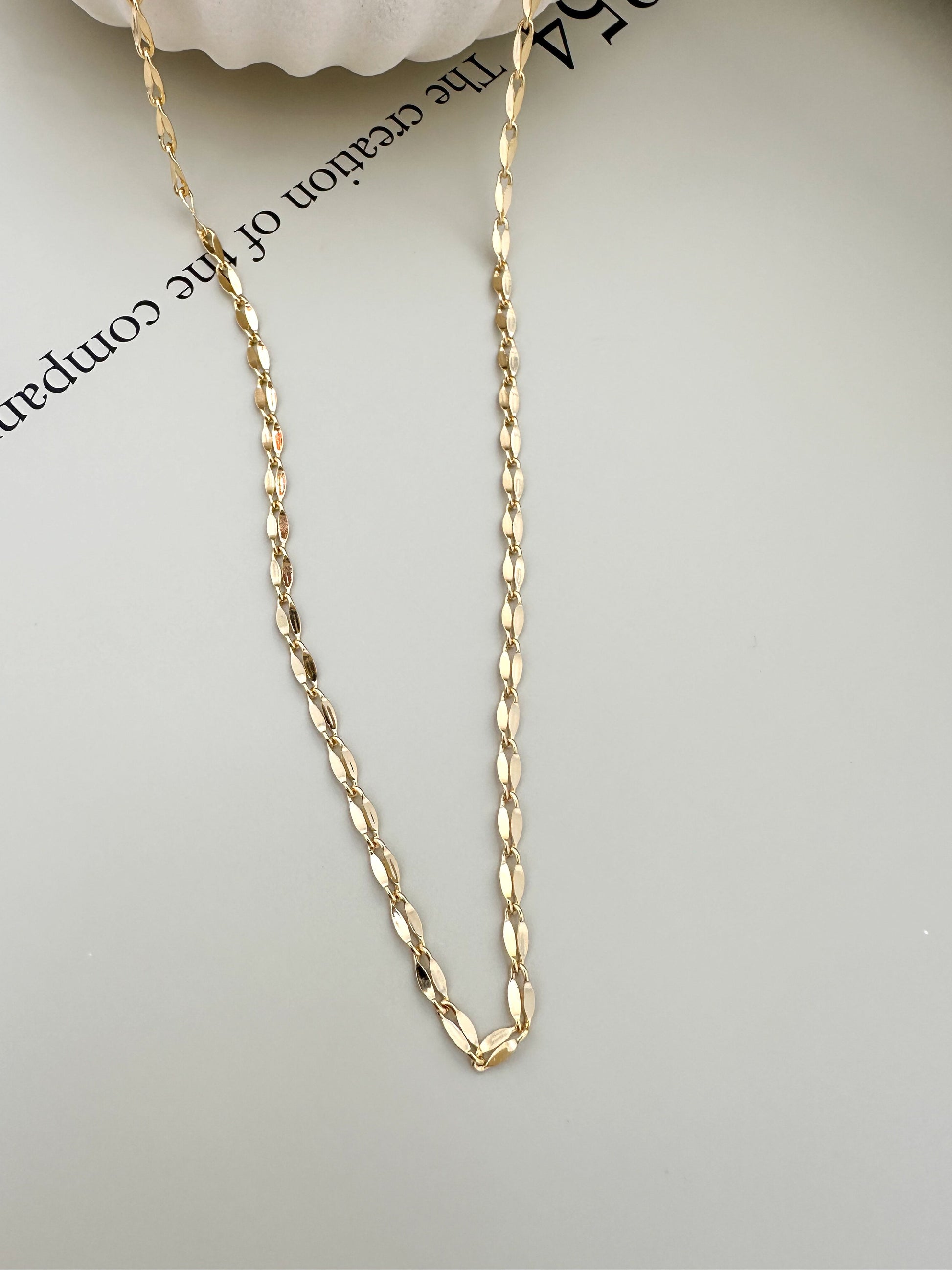 Velani Jewelry Corrente Luxe Necklace in 18K gold filled, handcrafted design showcasing chain details on a light surface.