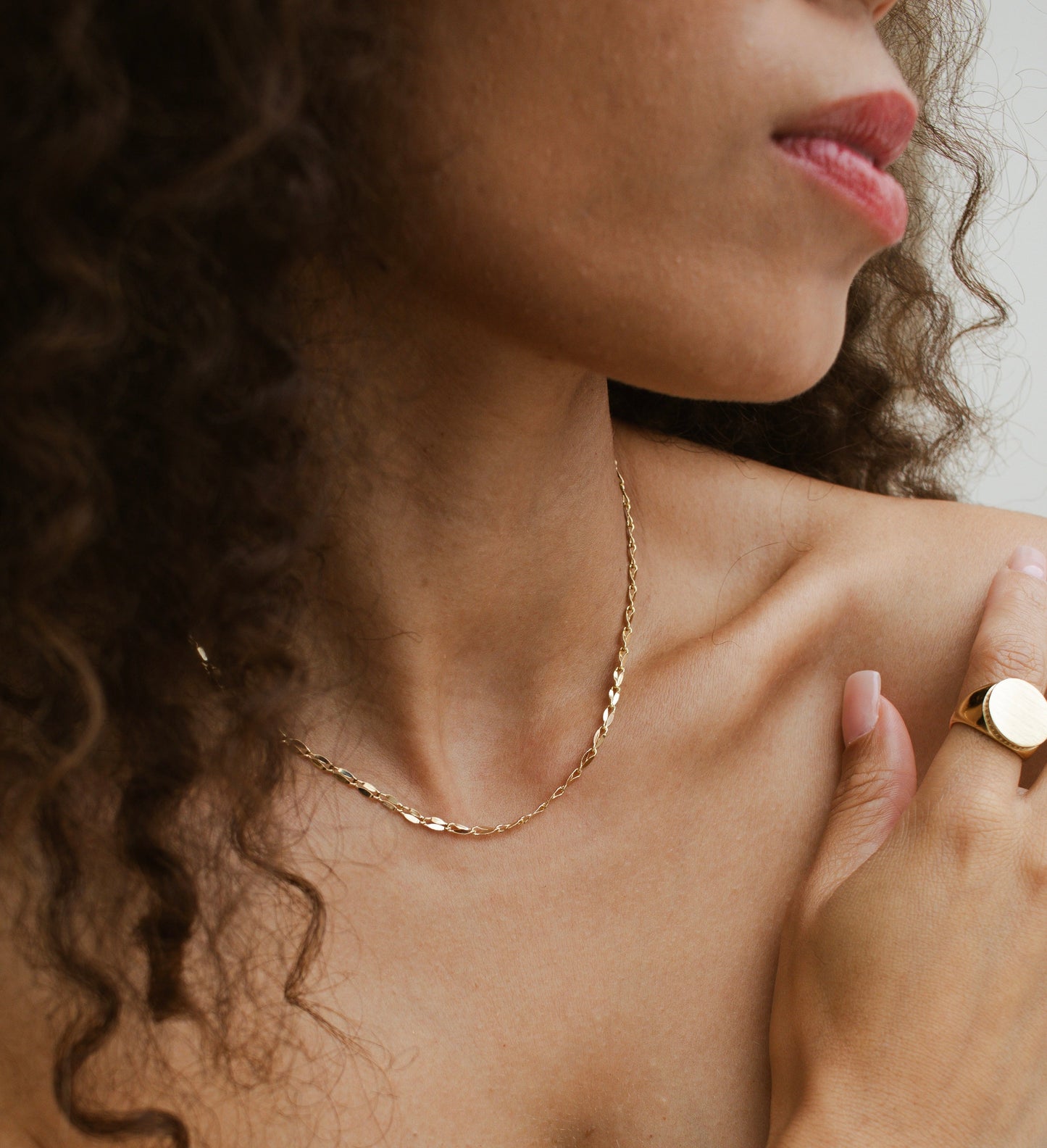 Velani Jewelry Corrente Luxe Necklace showcased on a model with curly hair, highlighting its elegance and charm.