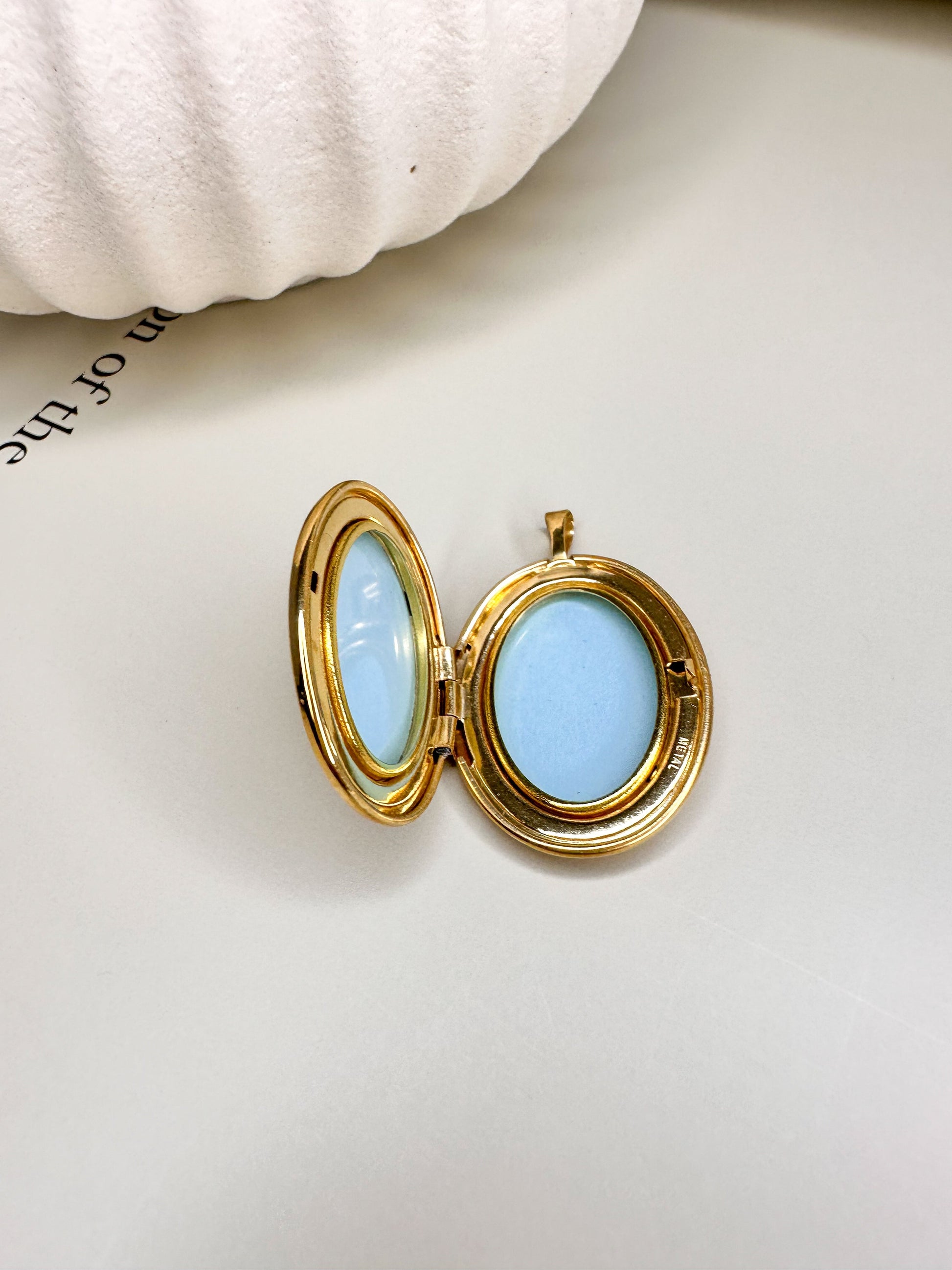 Open gold locket with blue interior by Velani Jewelry, perfect for personal keepsakes, shown on a neutral background.