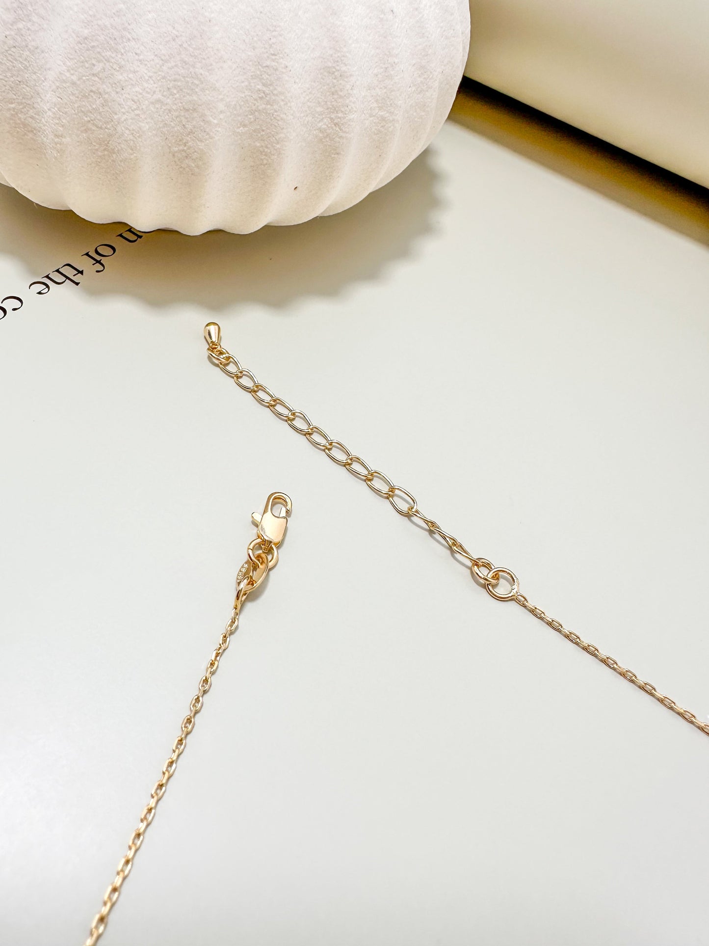 Close-up of a gold chain necklace with an extender clasp, showcasing the craftsmanship of Velani Jewelry's Dove Necklace.