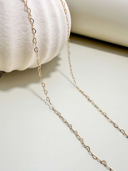 Gold filled dainty flat heart necklace on a neutral background, perfect for everyday wear, hypoallergenic and waterproof.