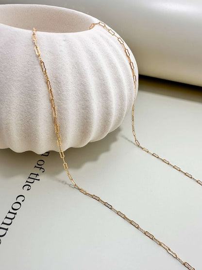 Velani Jewelry Gold Filled Flat Krinkle Necklace displayed near a textured vase, showcasing its elegant design.