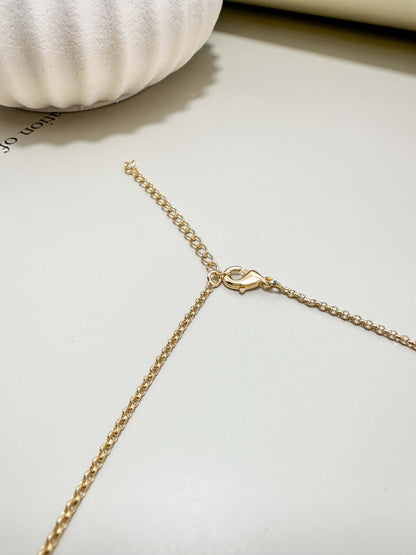 Close-up of Velani Jewelry lariat necklace gold filled chain clasp on a soft surface.