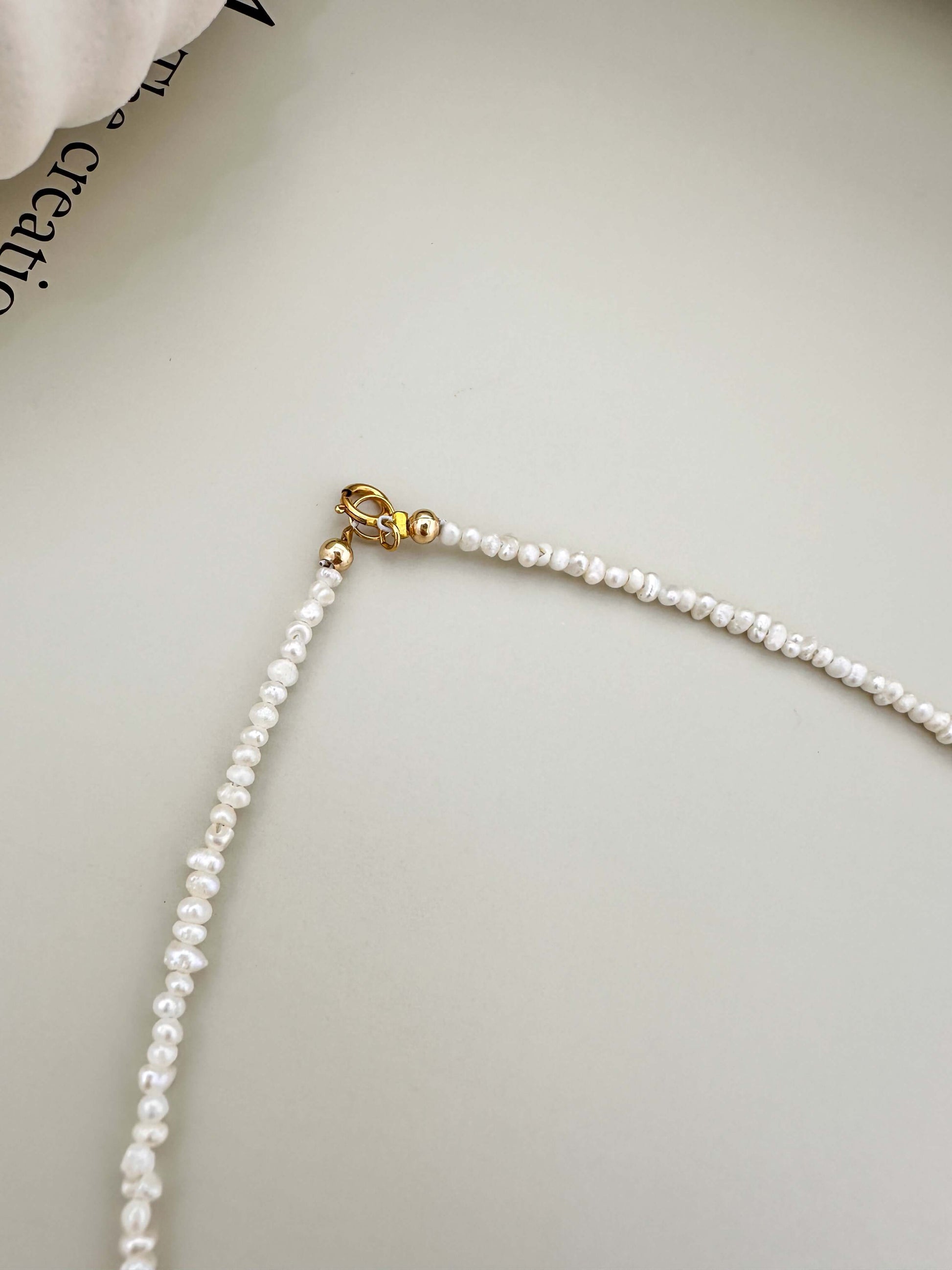 Close-up of Velani Jewelry Micro Freshwater Pearl Necklace with gold filled clasp, showcasing its hypoallergenic and waterproof features.
