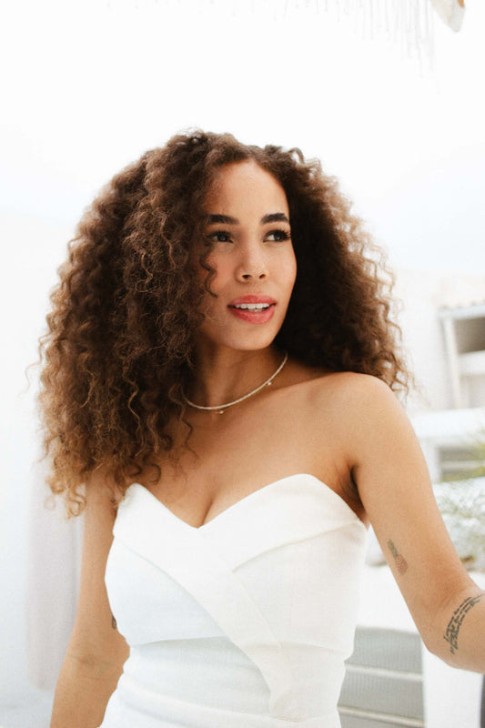 Beautiful woman with curly hair wearing a Velani Jewelry Micro Freshwater Pearl Necklace, styled for everyday wear.